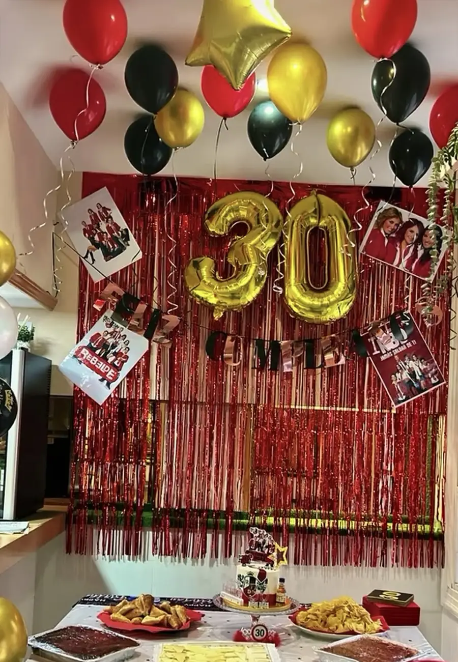 Decoración de cumpleaños con globos dorados y negros y cortina brillante